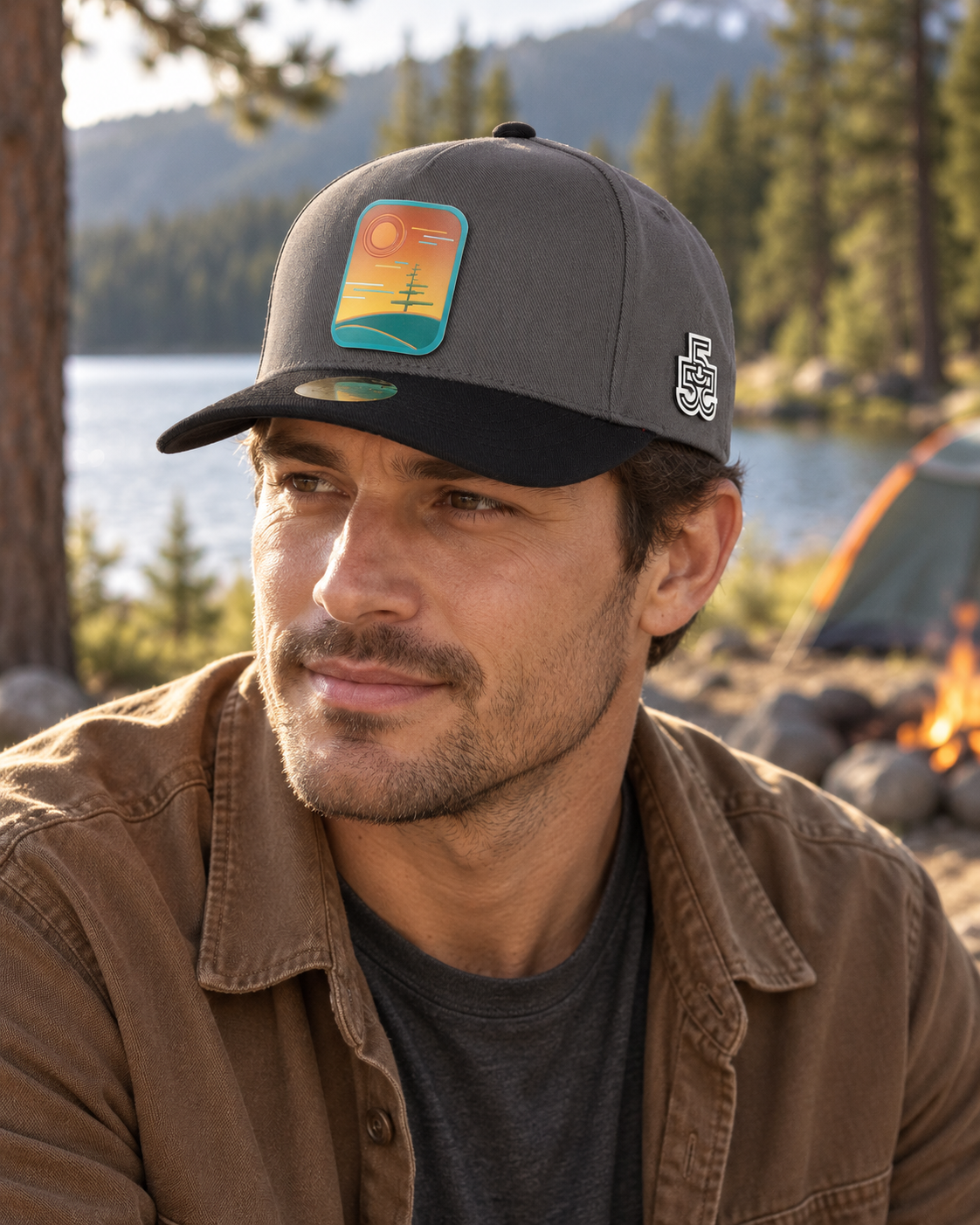 Man wearing the charcoal and black Quiet Witness cap at a lakeside campsite
